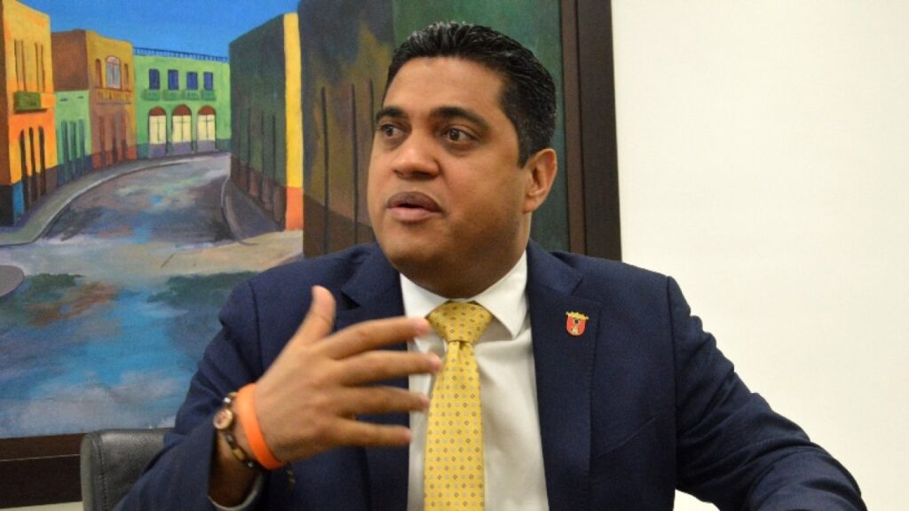 Kelvin Cruz reitera el veto a equipos haitianos y la Concacaf pospone el Violette-Portmore que iba a jugarse en Santiago Kelvin Cruz, ministro de Deportes y Recreación, con traje azul y corbata amarilla, gesticula mientras habla durante una entrevista (foto de archivo)
